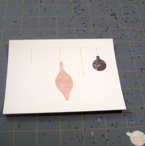 Using tape runner adhesive to apply ornament shapes to holiday card