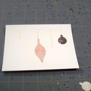 Using tape runner adhesive to apply ornament shapes to holiday card