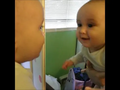 baby kissing himself in the mirror
