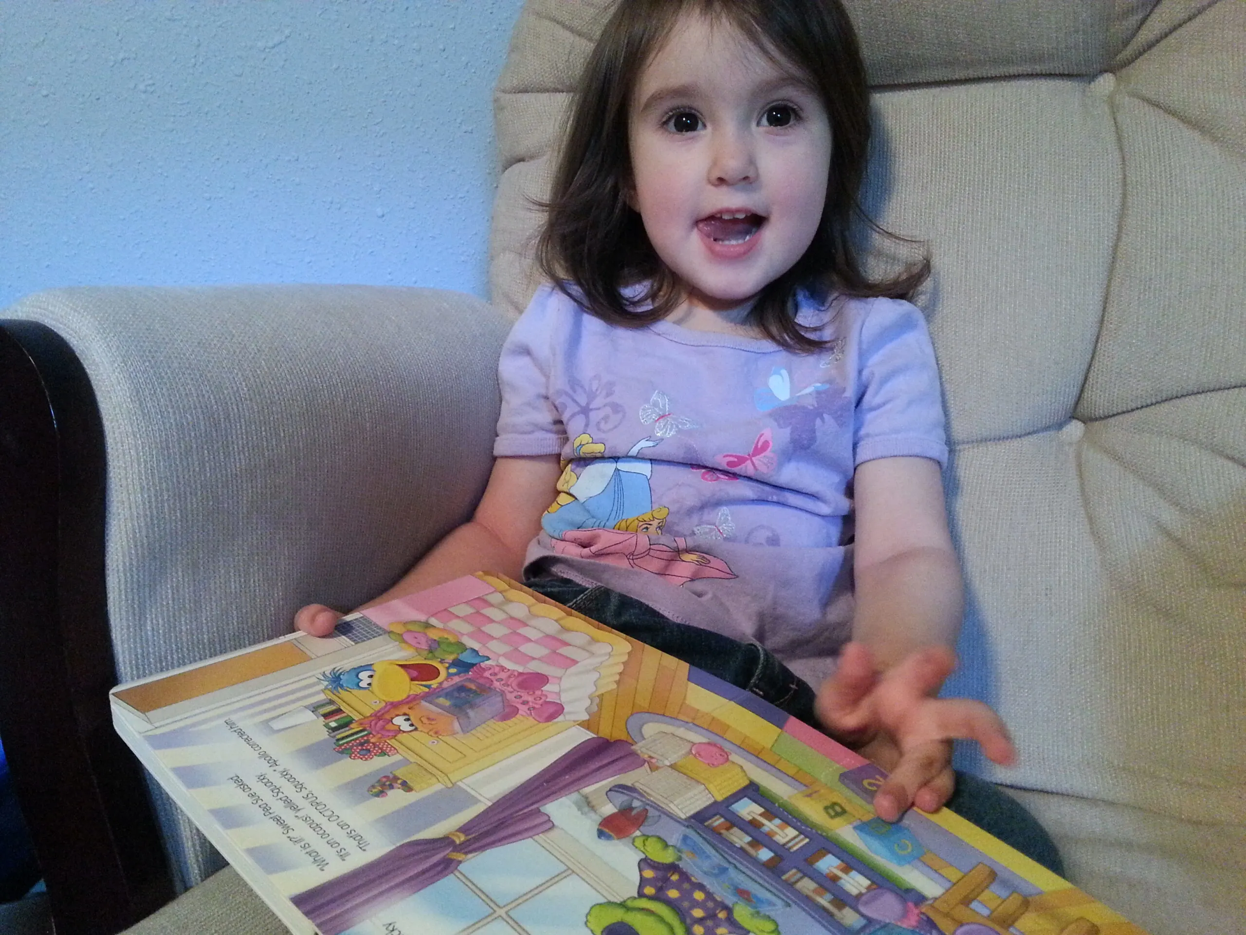 toddler girl sitting in chair with book