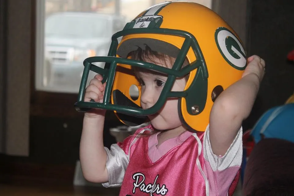 toddler girl wearing Packer helmet and pink jersey