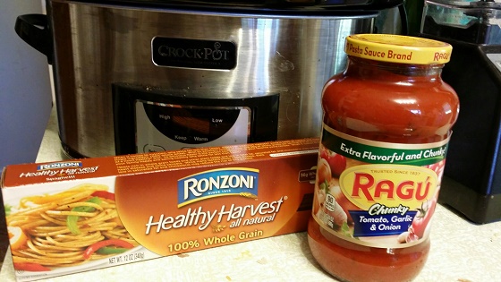 Crockpot, pasta noodles, and jar of sauce on counter.