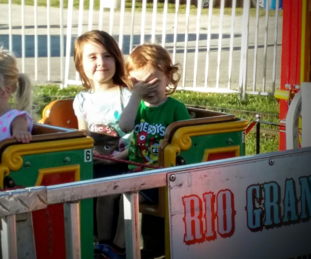 Little boy facepalming on a carnival train ride.