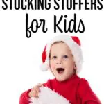 Surprised boy wearing red shirt and Santa hat reaching into a Christmas stocking.
