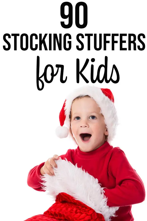 Surprised boy wearing red shirt and Santa hat reaching into a Christmas stocking.