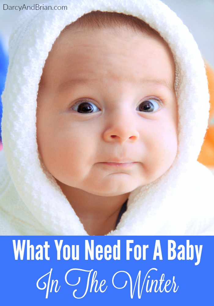 Close up of baby's surprised face while wearing a white winter jacket with hood on.