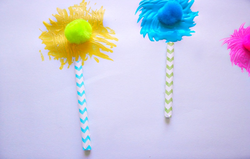 Yellow, blue and pink fork painted Truffula trees with matching pom poms in the center.