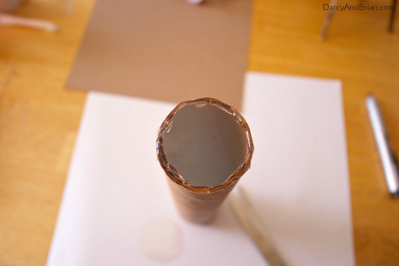 Hot glue plastic circle at one end of paper tube.