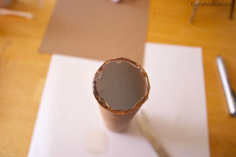 Hot glue plastic circle at one end of paper tube.