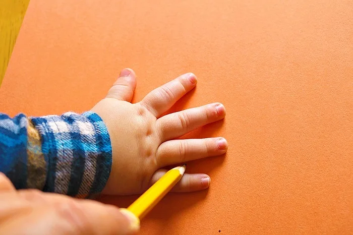 Tracing child's hand for craft project.