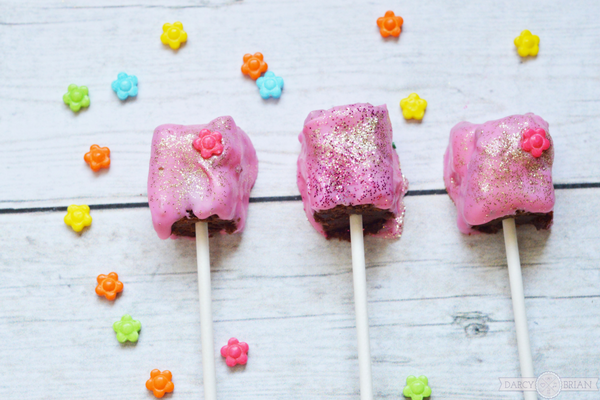 Whether you are planning a princess themed birthday party for girls or a tea party themed baby shower, these Princess Tea Party Glitter Brownie Pops are the ideal treat for your special event. Learn how to make these easy delicious decadent chocolate treats for your party! Click through for step by step instructions. Turn dessert into something magical!