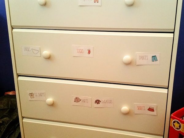 White dresser in kids' room with clothing labels on the drawers.