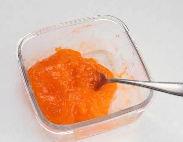 Mixing orange slime in a small clear container.