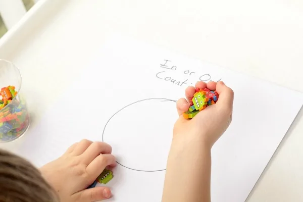 Show your child how to drop the erasers over the counting mat.