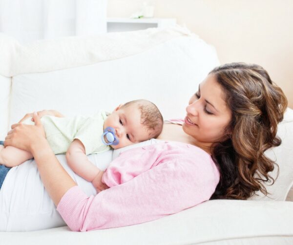 Happy mom laying down with content baby.