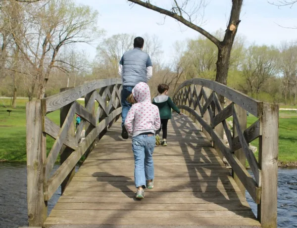 My family walking across a pedestrian bridge at a park.
