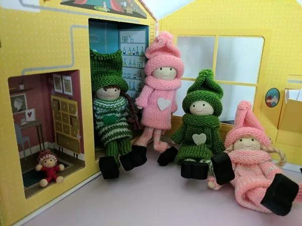 Pink and Green Kindness Elves posed by their house.