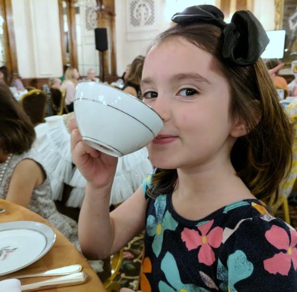 My daughter sipping hot chocolate from a tea cup.