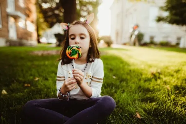 Author's daughter sitting in the grass with a colorful lollipop