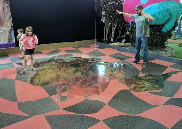 Artist designed mini golf at Can Can Wonderland looks like guests are on ledge of pit.