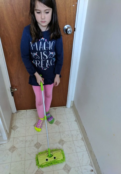 Author's daughter mopping the bathroom floor with kids mop.