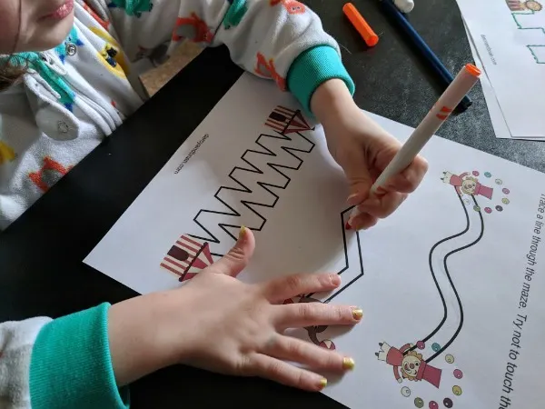 Preschooler practicing early writing skills by tracing lines on circus printable worksheet.