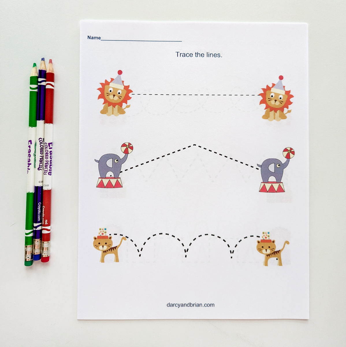 Circus line tracing printable with circus animals on it. A few colored pencils lay next to it.