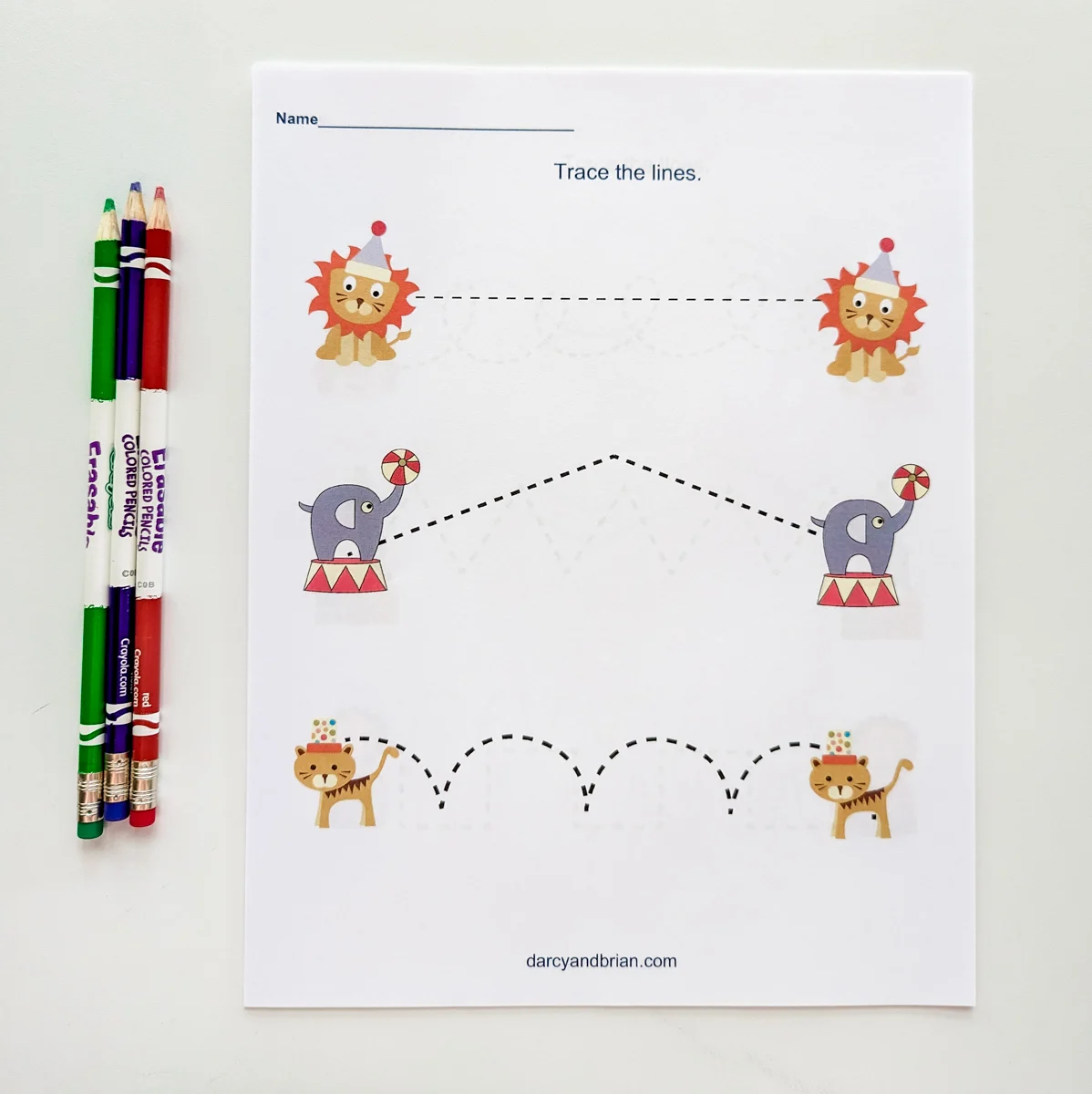 Circus line tracing printable with circus animals on it. A few colored pencils lay next to it.