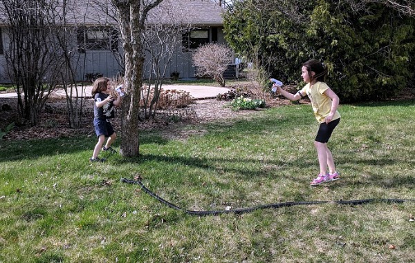 Playing laser tag outside and hiding behind a tree.