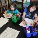 Two kids working on printable fairy tale workbook activity pages.