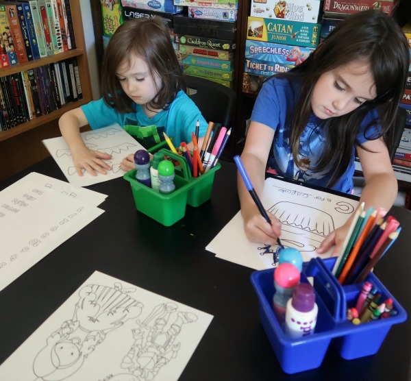 Two kids working on printable fairy tale workbook activity pages.