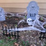Halloween cemetery decorations outside house.