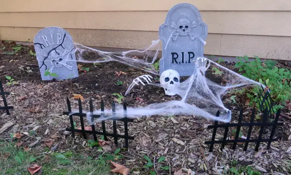 Halloween cemetery decorations outside house.