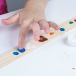 Using paint to create fingerprint planets on a paint stir stick.