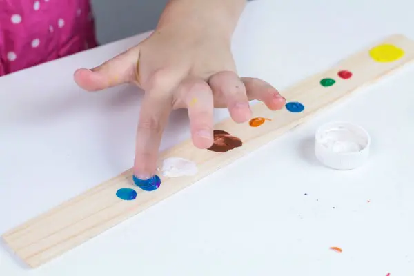 Using paint to create fingerprint planets on a paint stir stick.