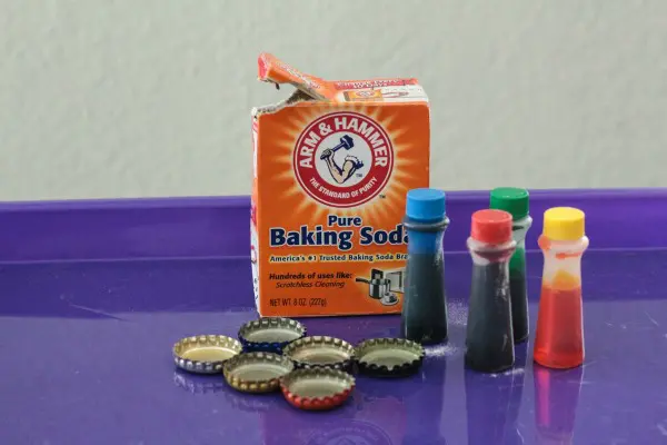 Supplies needed for this fizzy bottle caps science experiment: baking soda, bottlecaps, food coloring