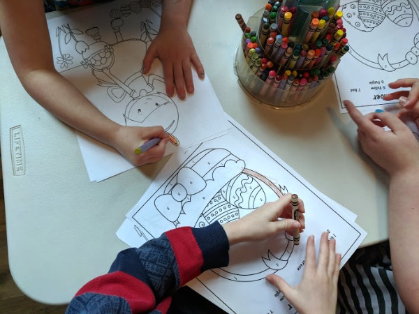 Kids coloring Easter basket color by number printables. A crayon tower is in the middle of the table.