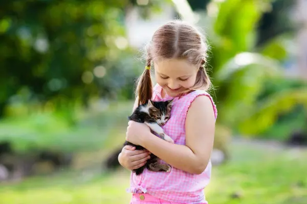 Little girl holding a kitten while outside