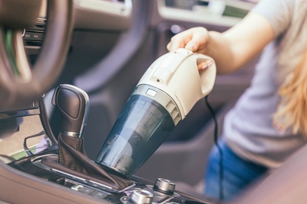 Woman vacuuming the inside of her car.