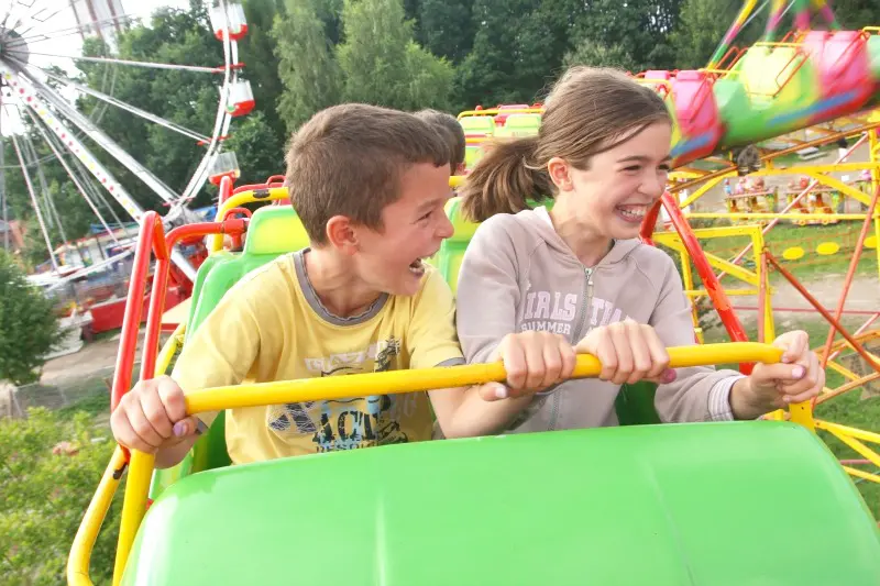 Kids riding roller coaster at an amusement park.
