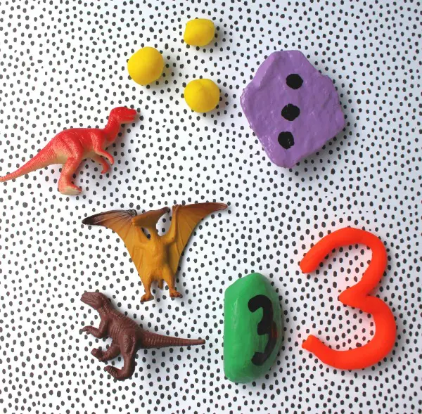 Using playdough and toys with the number 3 rock for a counting activity.
