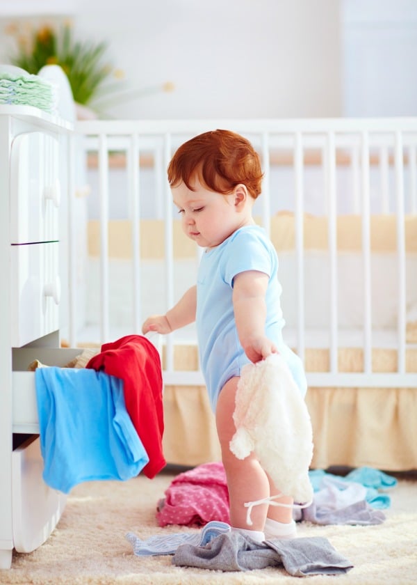 Young toddler pulling clothes out of dresser drawer.