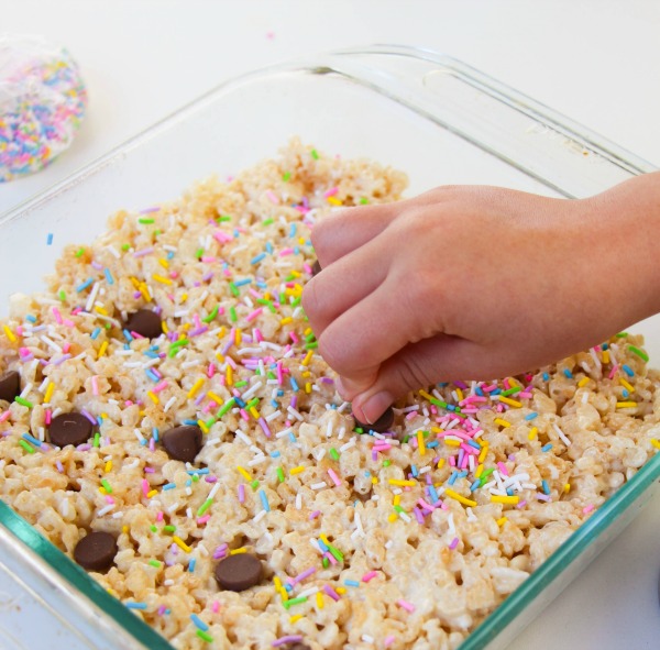 Adding chocolate chips to make unicorn poop crispy treats