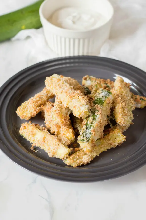 Oven baked zucchini fries on round black plate
