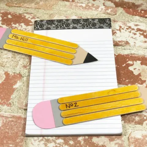 Two completed pencil crafts made with craft sticks and paper laying on notebook