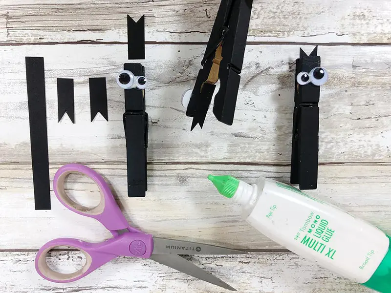 Cutting out ears and gluing them onto the black painted clothespins to make bats