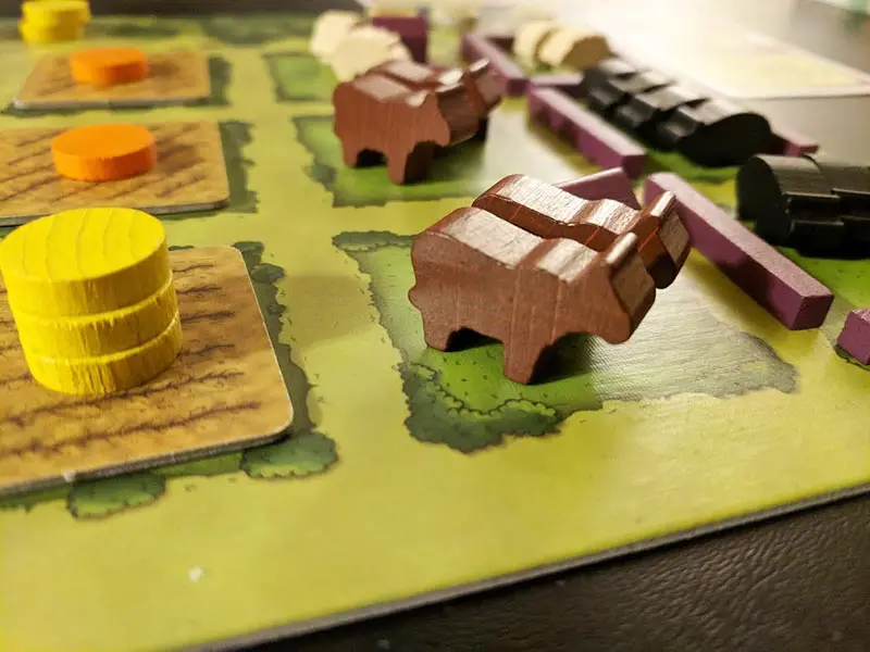 Close up of Agricola game board with fields and animal meeples.