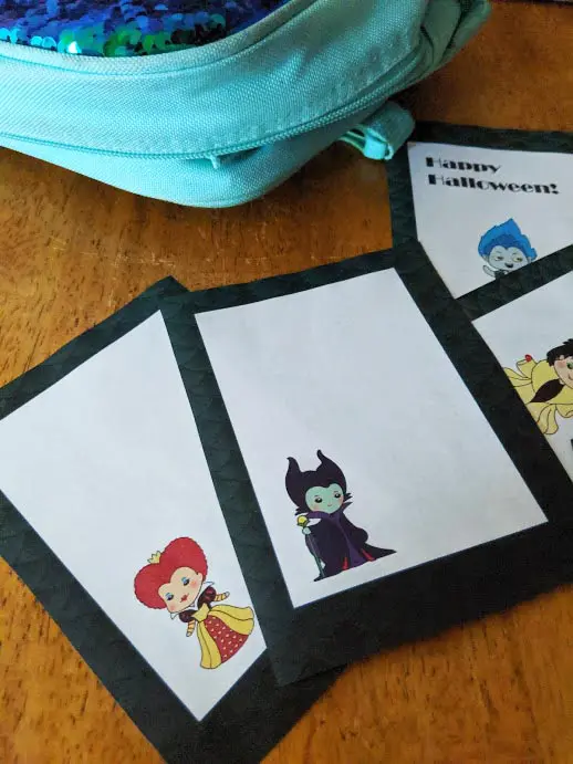 Blank lunch box notes with Queen of Hearts and Maleficent printed out and laying on table by lunchbox.