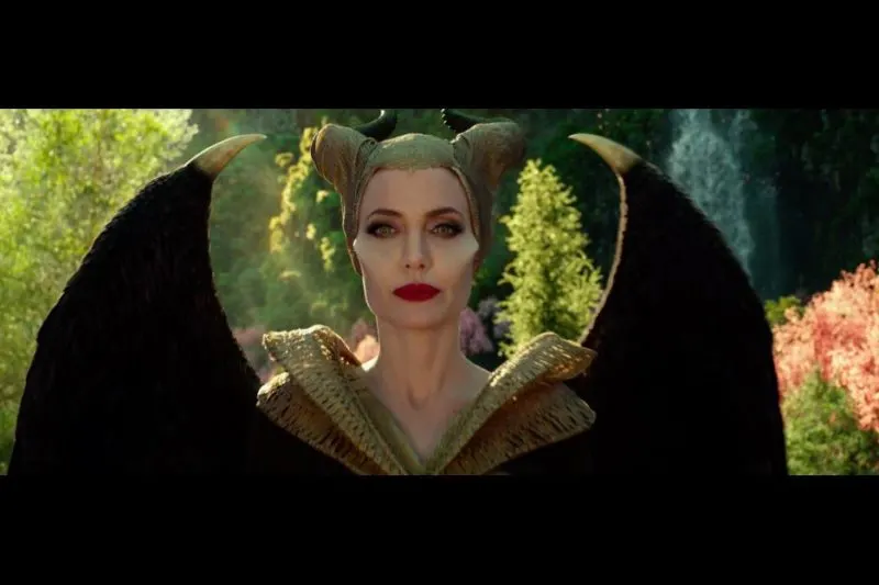 Maleficent standing, wearing tan robes and tan wrapped horns.