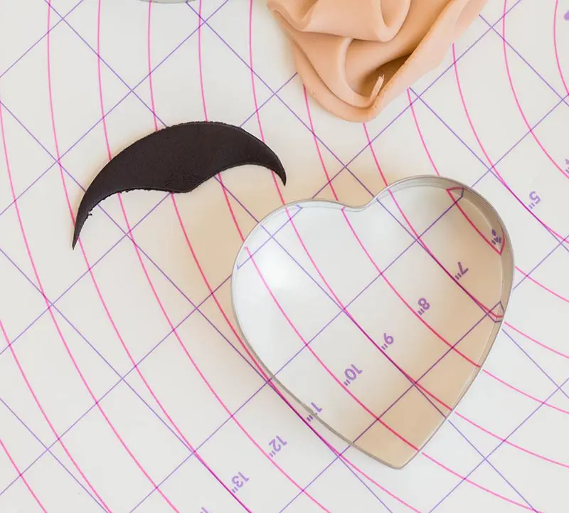 Demonstrating how to use heart cookie cutter to create hair with widows peak for fondant face